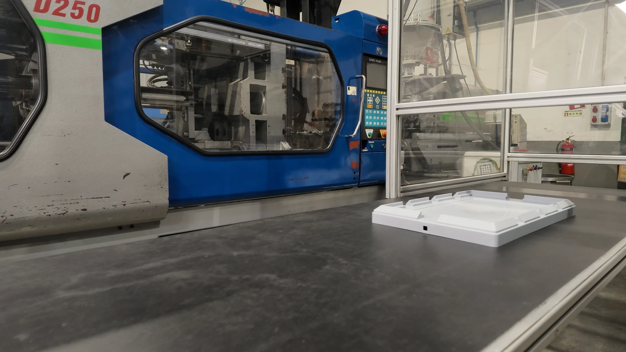 Máquina de injeção na fábrica da LinkPlas, com uma tampa acabada de moldar